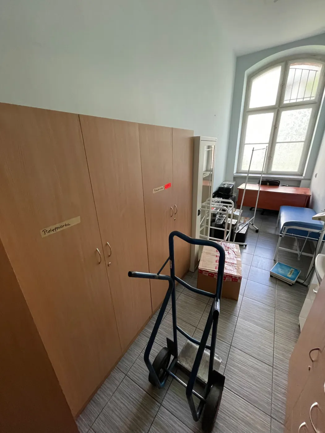 Gabinet pielęgniarki szkolnej z wózkiem transportowym i spakowanym wyposażeniem gotowym do przewiezienia
